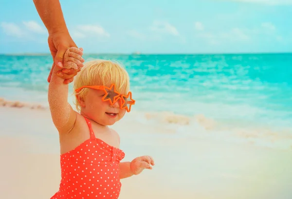 Bonito pouco bebê menina na praia segurando mãe mão, família na praia — Fotografia de Stock