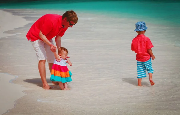 Vader en kinderen lopen op strand bij zee vakantie — Stockfoto