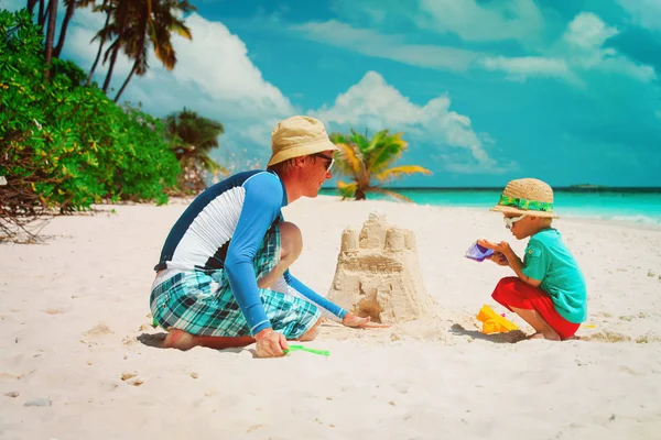 Vader en zoon gebouw kasteel op zand strand — Stockfoto