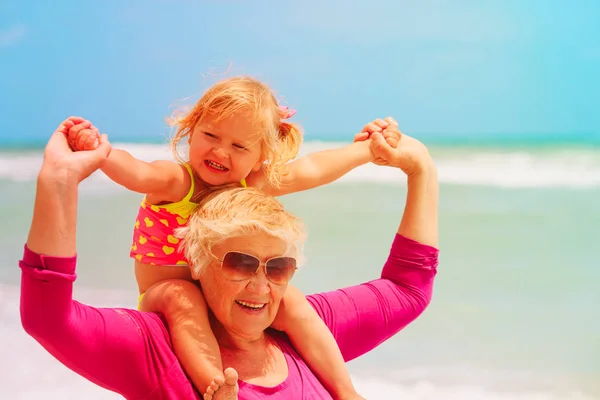 Glückliche Großmutter und kleines Mädchen spielen am Strand — Stockfoto