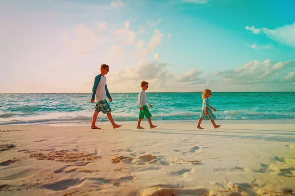 Vader en twee kinderen walking op strand — Stockfoto