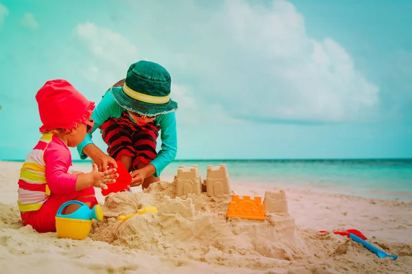 Bambino e ragazza giocare con sabbia sulla spiaggia — Foto Stock