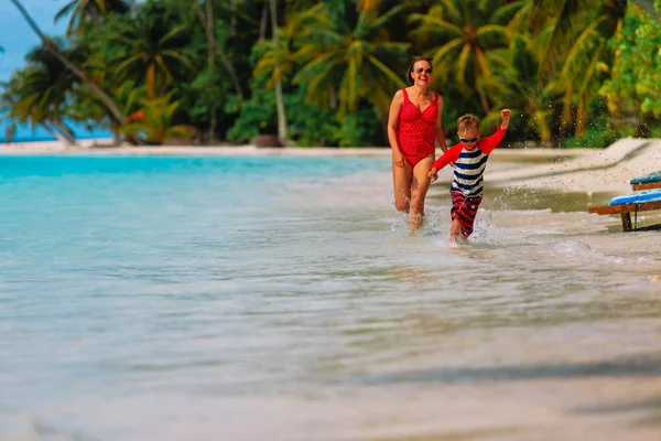 Moeder en zoon lopen in water op strand — Stockfoto