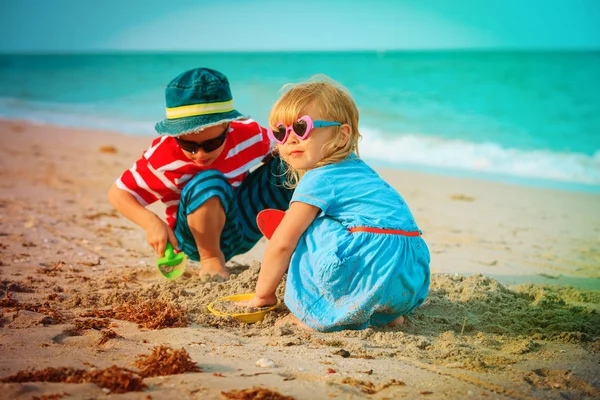 Mały chłopiec i dziewczyna grać z piaskiem na plaży — Zdjęcie stockowe
