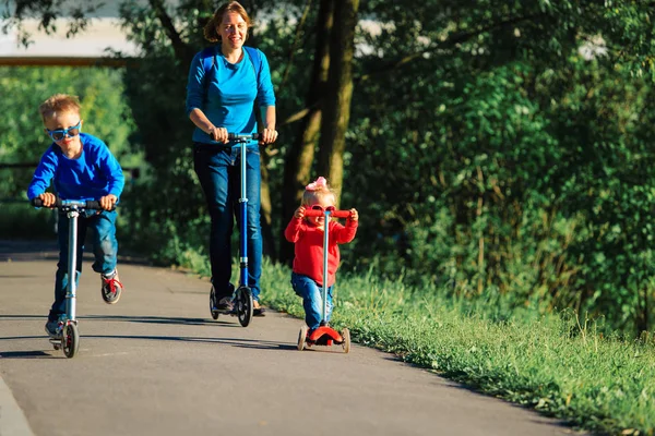 Мати з дітьми верхи на скутерах у природі — стокове фото