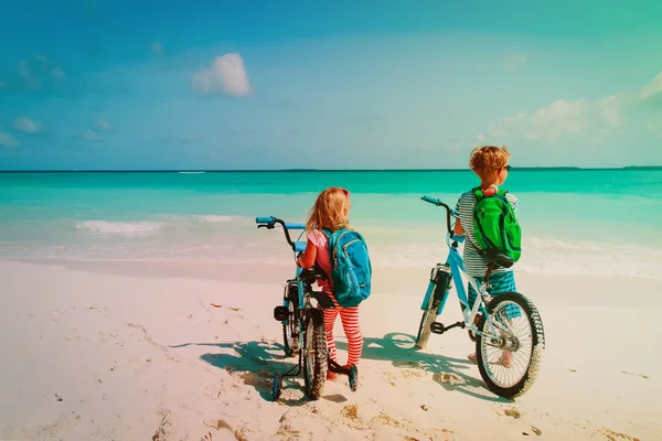 Heureux petit garçon et fille balade vélo sur la plage — Photo