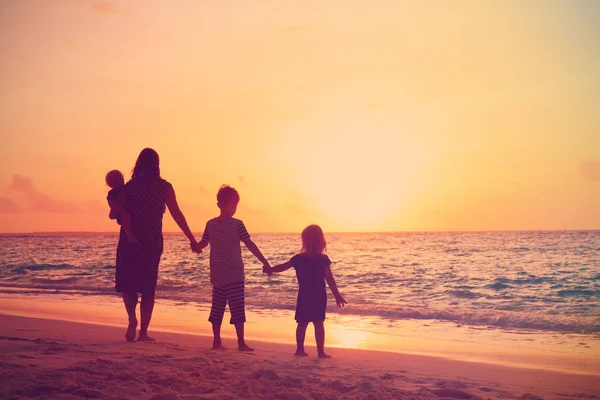 Ibu dengan anak-anak berjalan di pantai saat matahari terbenam — Stok Foto