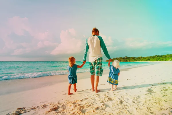 Vater und zwei Kinder spazieren am Strand — Stockfoto