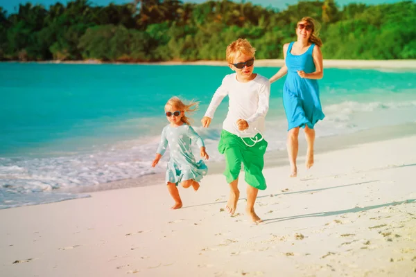 Anne çocuklarla oynamak üzerinde çalışma tropikal plaj — Stok fotoğraf