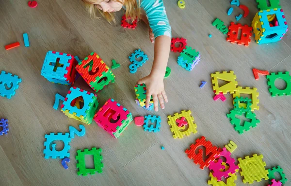 Liten flicka lära sig siffror och former, leka med pussel — Stockfoto