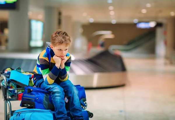 Niño esperando en el aeropuerto sentado en el equipaje — Foto de Stock