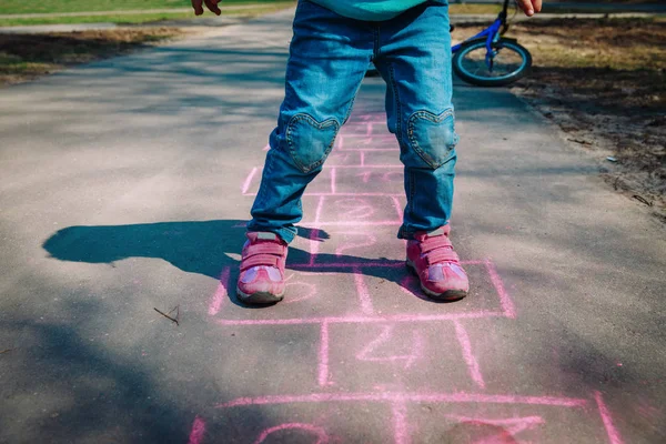 Menina jogar hopscotch no playground — Fotografia de Stock