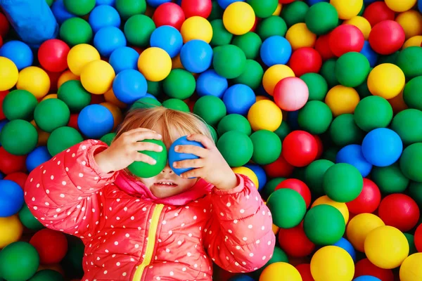 Petite fille jouer dans la piscine rempli de boules colorées — Photo