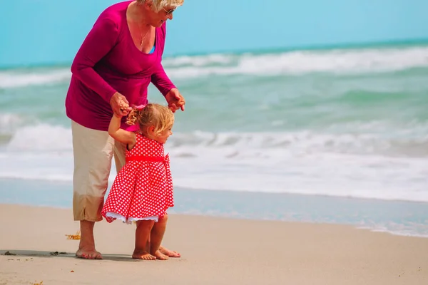 Gelukkig grootmoeder en weinig kleindochter spelen op strand — Stockfoto