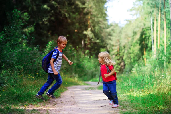 Menino e menina feliz com mochilas na natureza, férias escolares — Fotografia de Stock