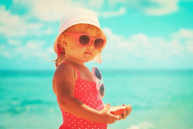 Tatlı küçük kız kumsalda kumla oynuyor.