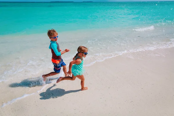 Petite fille et garçon courir jouer avec de l'eau sur la plage — Photo