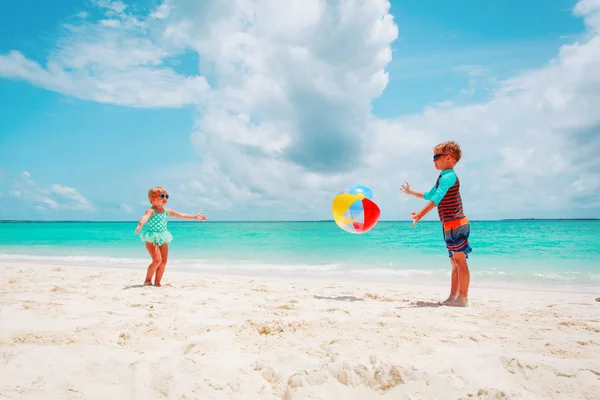 Klein meisje en jongen spelen bal op strand — Stockfoto