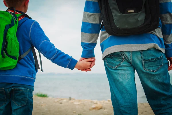 Padre e hijo pequeño tomados de la mano en la playa del mar — Foto de Stock