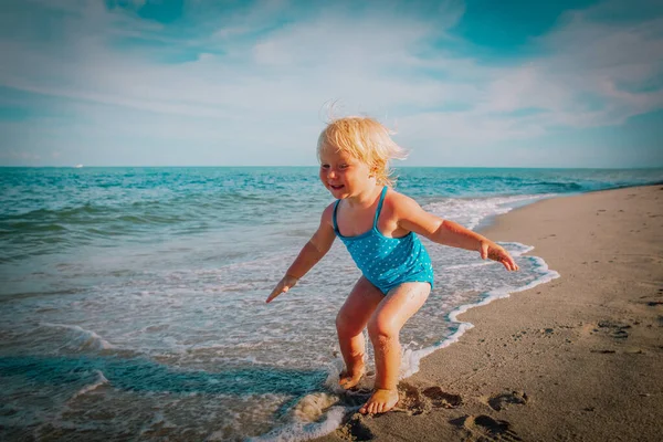 Bonito feliz menina jogar com água na praia — Fotografia de Stock