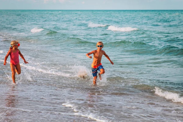 Gelukkig meisje en jongen hardlopen op het strand, kinderen spelen met golven — Stockfoto