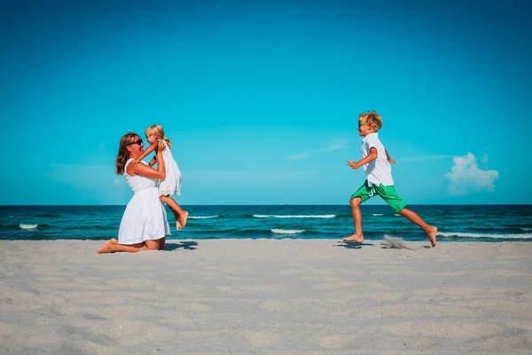 Gelukkig moeder met zoon en dochter spelen op het strand, familie zorg — Stockfoto