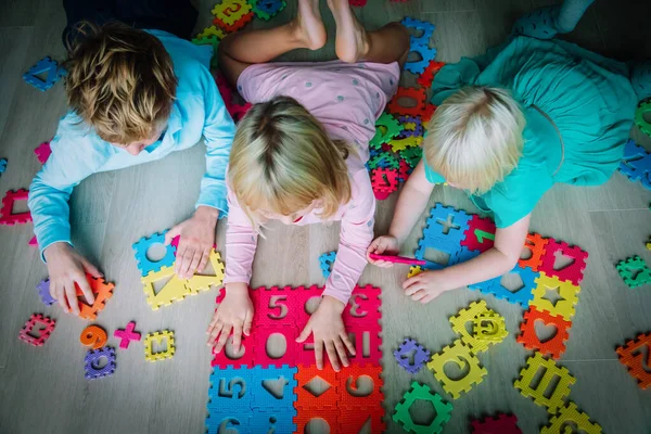 Дети играют с головоломками, мальчик и девочка узнать формы и цифры, концепция образования — стоковое фото