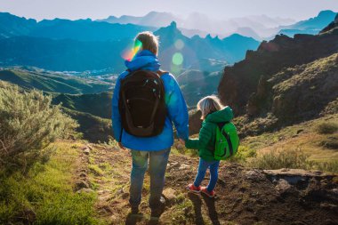Baba ve küçük kızı gün batımında dağlarda geziyorlar.