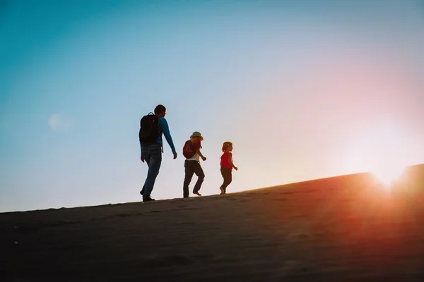 Silhuetas de pai com filho e filha caminhadas ao pôr do sol — Fotografia de Stock