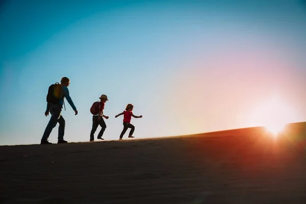 Silhuetas de pai com filho e filha caminhadas ao pôr do sol — Fotografia de Stock