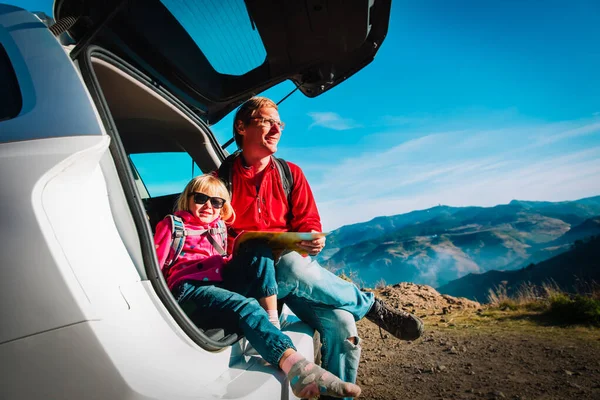 family travel by car - father with little daughter looking at map in mountains