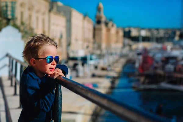 Милый маленький мальчик путешествует по Мальте, ребенок смотрит на лодки на набережной — стоковое фото