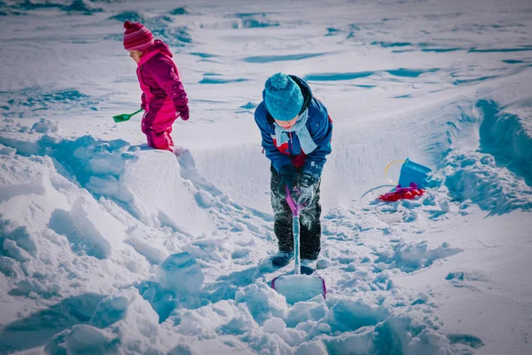 Crianças menino e menina cavando neve no inverno, crianças diversão sazonal — Fotografia de Stock