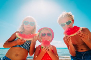 Kumsalda karpuz yiyen güzel kız ve erkek çocuklar.