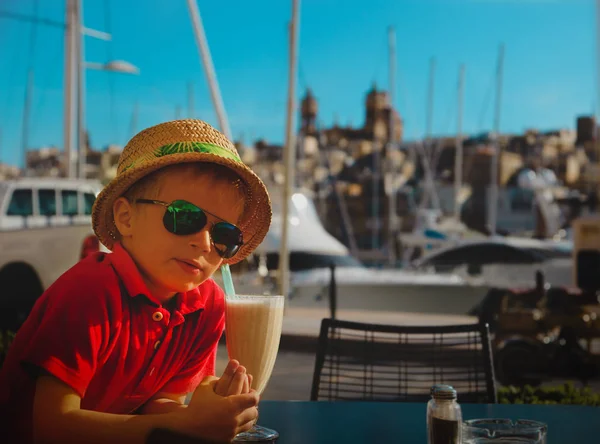 Милый маленький мальчик выпивает в кафе на набережной Мальты, концепция путешествия — стоковое фото