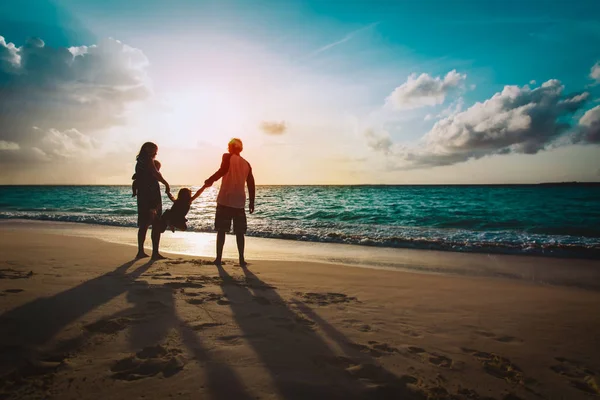 Familia feliz con los niños en el juego en la playa del atardecer — Foto de Stock