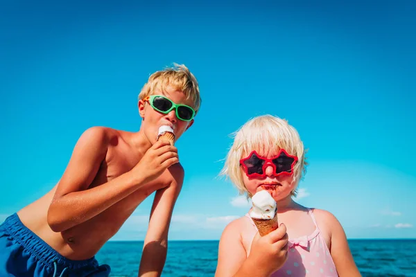 Schattig gelukkig jongen en meisje eten ijs op het strand — Stockfoto