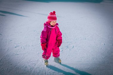 Mutlu küçük kız kışın paten kaymayı öğreniyor.