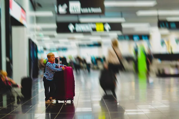 Маленький хлопчик з валізами подорожі в зайнятому аеропорту — стокове фото
