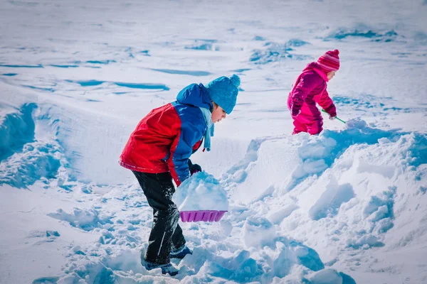 Crianças menino e menina cavando neve no inverno, crianças diversão sazonal — Fotografia de Stock