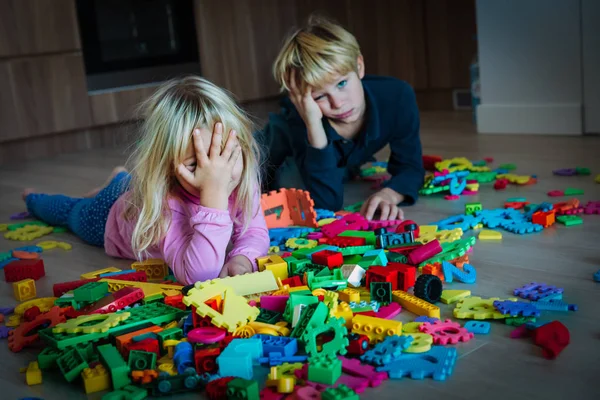 Menino e menina cansado estressado exausto com brinquedos espalhados dentro de casa — Fotografia de Stock