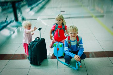 Çocuklar, oğlanlar ve kızlar. Bavulları havaalanında bekliyor. Aile seyahati.
