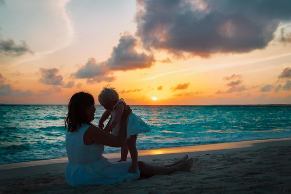 Mère heureuse et petite fille jouent à la plage du coucher du soleil — Photo