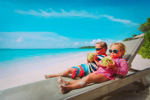 Mały chłopiec i dziewczynka picia kokosowe na plaży — Zdjęcie stockowe