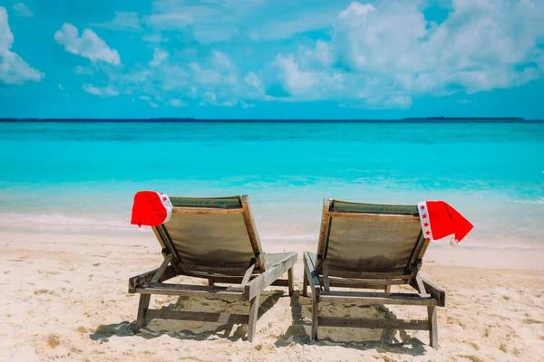 Christmas on beach-chair lounges with Santa hats at sea — стоковое фото