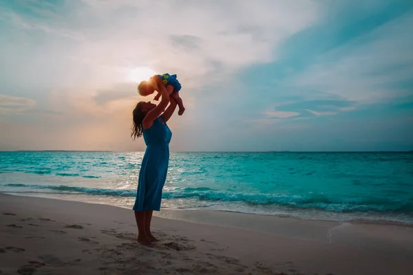 Mãe feliz e filhinha brincam na praia do pôr do sol — Fotografia de Stock