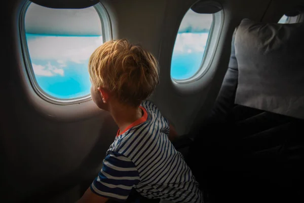 Niño viajando en avión mirando por la ventana — Foto de Stock