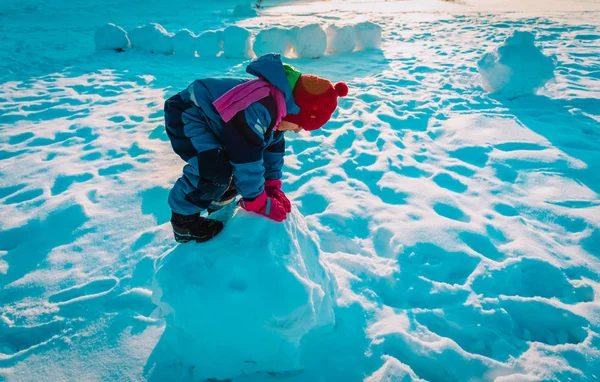 Klein meisje bouwen sneeuwballen in de winter natuur — Stockfoto