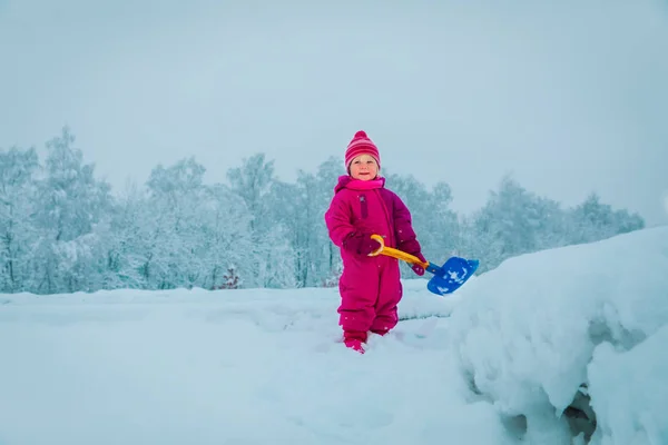 Nettes kleines Mädchen schaufelt mit Schaufel Schnee, Kinder spielen im Winter — Stockfoto