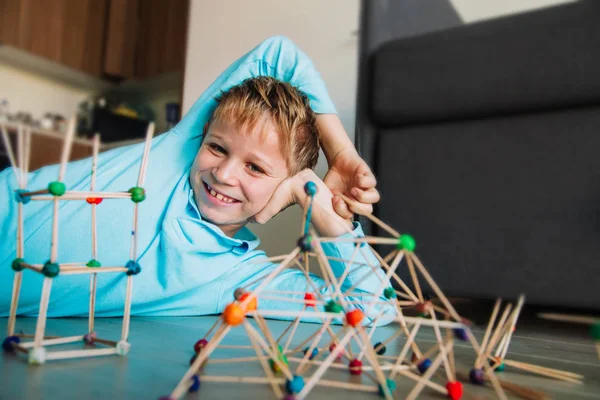 Χαρούμενο αγόρι κάνει γεωμετρικά σχήματα από ραβδιά και πηλό, μηχανική και Stem — Φωτογραφία Αρχείου